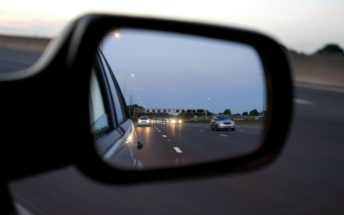 Blick in den Seitenspiegel auf einer dreispurigen Autobahn Blick in den Seitenspiegel auf einer dreispurigen Autobahn